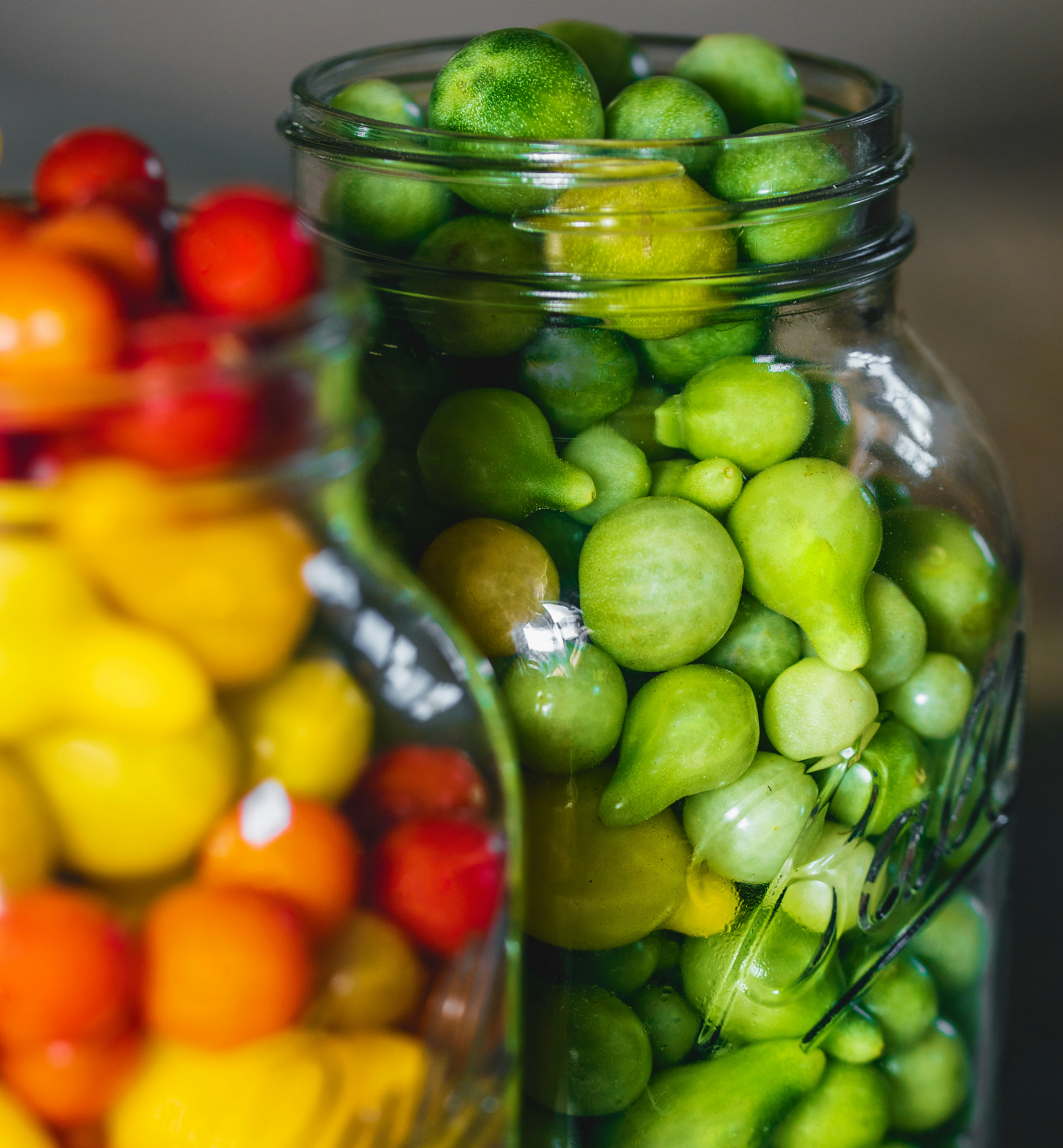 green and yellow round fruits in clear glass jar